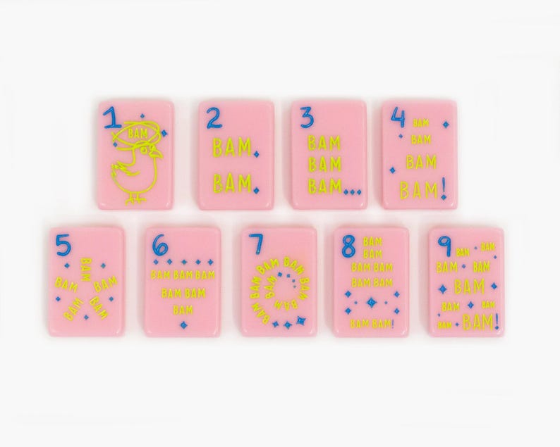 May include: A set of nine rectangular pink tiles, each featuring a blue number from one to nine and yellow text reading BAM. The tiles display various arrangements of the word BAM, small blue stars, and a yellow chicken illustration on the number one tile.
