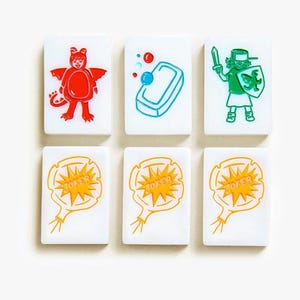 May include: Six white rectangular mahjong tiles arranged in two rows. The top row features a red dragon costume, a blue bar of soap with bubbles, and a green knight with a sword and shield. The bottom row shows three identical yellow joker balloons.
