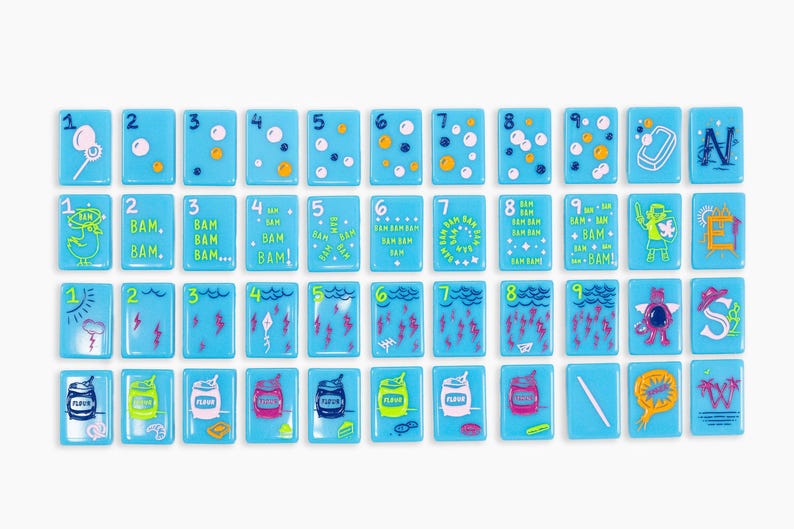 May include: A collection of forty-four rectangular light blue tiles arranged in four rows. Each tile features colourful illustrations, numbers, or letters. The designs include bubbles, lightning bolts, cans labelled flour, and various cartoon characters.