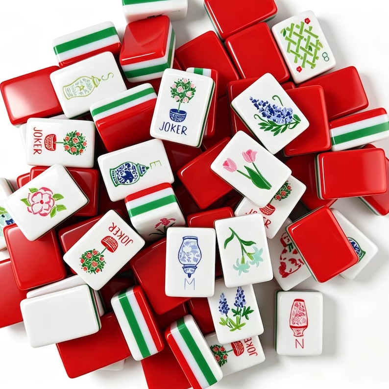 May include: A collection of rectangular mahjong tiles featuring a mix of solid red backs, red and green striped sides, and white faces decorated with colorful illustrations of flowers, vases, and the word JOKER in black text.