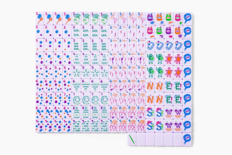 Pu&ograve; includere: Un set di tessere rettangolari bianche da mahjong disposte in una griglia, caratterizzate da grafiche stampate colorate che includono i numeri da uno a nove, palloncini, fulmini, fumetti in stile comico con il testo BAM e varie altre icone.