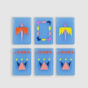 May include: Six rectangular light blue tiles arranged in two rows. The top row features two tiles with orange and yellow winged designs and one central tile with a colorful circular border. The bottom row shows three tiles labeled JOKER.