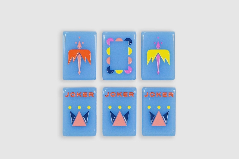 May include: Six rectangular light blue tiles arranged in two rows. The top row features two tiles with orange and yellow winged designs and one central tile with a colorful circular border. The bottom row shows three tiles labeled JOKER.