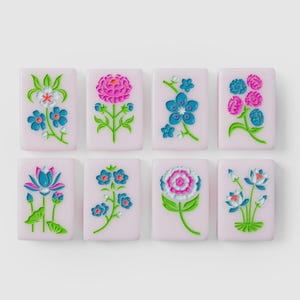Puede incluir: Ocho baldosas rectangulares de color rosa claro dispuestas en dos filas, cada una con un dise&ntilde;o floral en relieve &uacute;nico en colores vibrantes como azul, rosa, verde y blanco. Las baldosas tienen un acabado liso y motivos bot&aacute;nicos.