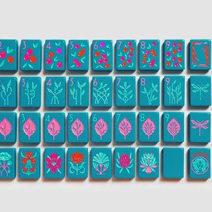 K&ouml;nnte beinhalten: Ein Set aus rechteckigen, blaugr&uuml;nen Mahjong-Spielsteinen, die in einem Raster angeordnet sind. Die Steine zeigen bunte Illustrationen von Beeren, Bambus, Bl&auml;ttern, Blumen, Libellen sowie Text wie North, East, West, South und ein Gesichtssymbol.