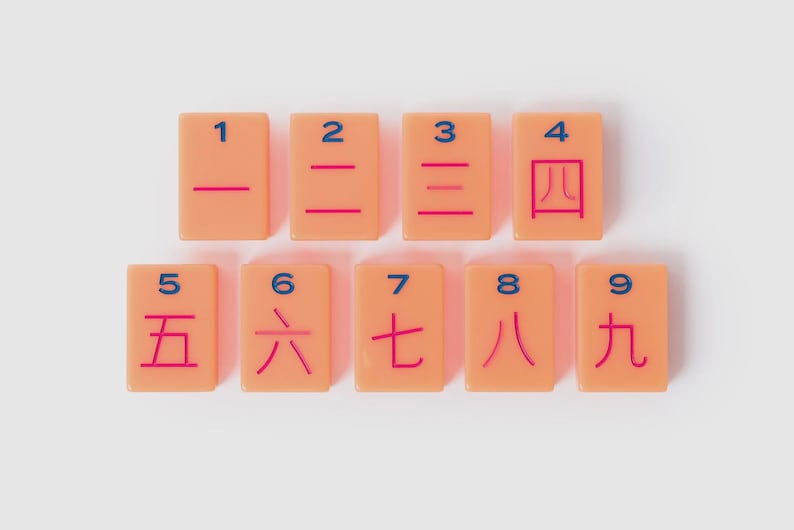 May include: A set of nine rectangular peach-colored tiles arranged in two rows. Each tile features a blue Arabic numeral from 1 to 9 at the top and a corresponding red Chinese character representing the same number centered below the numeral.