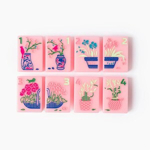 Puede incluir: Ocho baldosas rectangulares de color rosa dispuestas en dos filas, cada una con una ilustraci&oacute;n floral o vegetal &uacute;nica en azul, verde y rosa, con un n&uacute;mero verde correspondiente del uno al cuatro en la esquina superior.