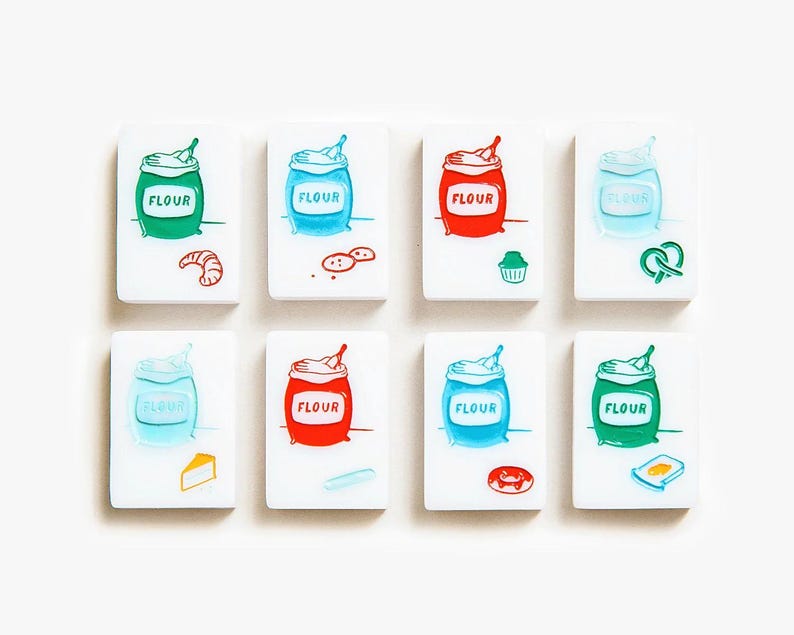 May include: Eight rectangular white tiles featuring colorful illustrations of flour sacks and various baked goods. Each tile displays a sack labeled "FLOUR" in red, green, or blue, accompanied by icons of a croissant, cookies, muffin, pretzel, cheese, bread, donut, or toast.