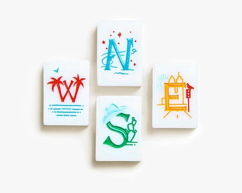 May include: Four rectangular white tiles representing cardinal directions. The W tile features red palm trees, the N tile has a blue letter with red stars, the E tile displays a yellow city skyline with a bird, and the S tile shows a green letter with a cactus.