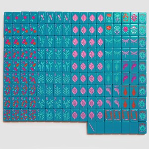K&ouml;nnte beinhalten: Ein Set aus blaugr&uuml;nen Mahjong-Spielsteinen in einem Raster angeordnet, mit eingravierten Motiven von nummerierten Fr&uuml;chten, botanischen Elementen, Libellen, Himmelsrichtungen und Joker-Steinen, verziert mit rosa, roter und hellblauer Tinte.