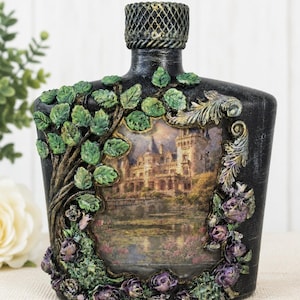 Op de afbeelding: Zwarte decoratieve fles met een kasteelscène. De fles heeft een getextureerde afwerking, een gedetailleerde kasteelafbeelding en is versierd met gebeeldhouwde bladeren en paarse rozen. De hals van de fles heeft een decoratieve dop.