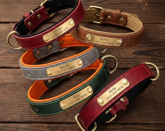 May include: A collection of personalized leather dog collars in various colors, including red, brown, green, and gray. Each collar features a brass nameplate with a dog's name and phone number. The collars have brass hardware and are displayed on a wooden surface.
