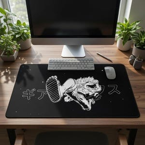 May include: Black rectangular desk mat featuring a white graphic of a foot and a mythical creature with Japanese text. The desk mat is placed on a wooden desk with a computer, keyboard, and mouse.