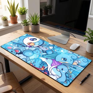 Peut inclure: Un tapis de souris rectangulaire bleu avec un motif de dessins animés de diverses créatures bleues. Le tapis a une bordure noire et est posé sur un bureau en bois. Un écran d'ordinateur, une souris et un stylo sont également visibles.