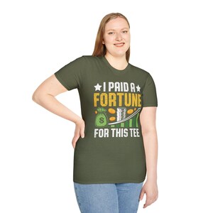 Puede incluir: Camiseta verde oliva con el texto "I PAID A FORTUNE FOR THIS TEE". El diseño incluye una bolsa de dinero, monedas y un gráfico ascendente, todo en un diseño divertido.
