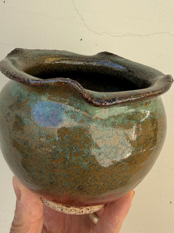 Intentionally 'deformed' rim with green-brown glaze — this small jar leans into wabi-sabi imperfection in a way that makes it genuinely interesting and conversation-starting.