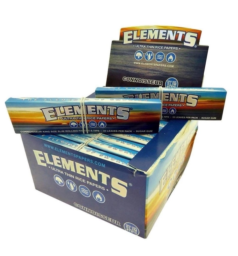 May include: A display box of Elements ultra-thin rice papers. The box is blue with white text and a sunset design. The brand name is prominently displayed. Individual packs are secured with rubber bands.