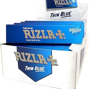 Può includere: Un'esposizione di scatole di cartine Rizla+ Thin Blue blu e bianche. Le scatole presentano il nome del marchio in lettere argentate, le parole "Thin Blue" e "King Size Slim". La scatola superiore ha un piccolo display con lo stesso marchio.