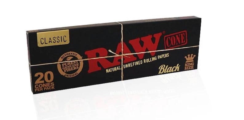 May include: A rectangular black box of RAW Black King Size cones featuring red and gold text. The packaging displays the text CLASSIC, RAW, CONE, 20 CONES PER PACK, NATURAL UNREFINED ROLLING PAPERS, and a circular logo with the words AUTHENTIC PUREST GENUINE FIBERS.