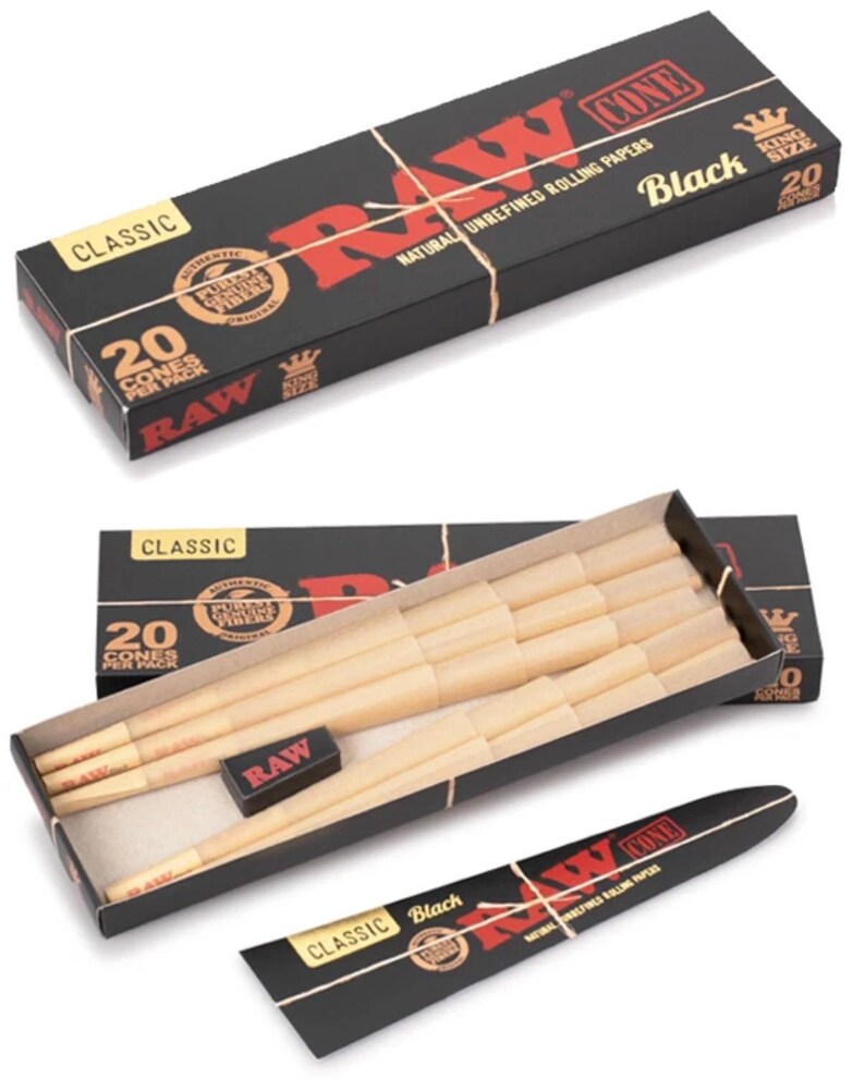 May include: A black rectangular box labeled RAW Classic Black King Size containing 20 pre-rolled paper cones. The open box reveals light tan paper cones arranged in rows, a small black rectangular packing tool, and a separate black paper sleeve.