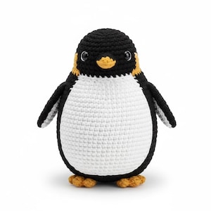 Könnte beinhalten: Ein handgefertigtes gehäkeltes Pinguin-Spielzeug. Der Pinguin hat einen schwarzen Kopf und Flügel, einen weißen Körper und gelb-orangefarbene Akzente an Schnabel und Füßen. Das Spielzeug ist mit einem festen Stichmuster gefertigt.
