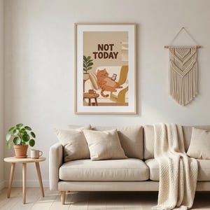 Könnte beinhalten: Ein gerahmter Kunstdruck mit dem Text "NOT TODAY" zeigt eine Illustration einer entspannten orangefarbenen Katze auf einem Sofa, die ein Telefon hält. Der Druck ist in einem hellen Holzrahmen, und die Szene spielt in einem gemütlichen Wohnzimmer.