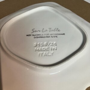 Peut inclure: Le dessous d'un plat en c&eacute;ramique blanc portant l'inscription Sur La Table, NOT SUITABLE FOR MICROWAVE, DISHWASHER SAFE, 9156/21 et MADE IN ITALY grav&eacute;e et imprim&eacute;e &agrave; l'encre noire au centre de la base de forme carr&eacute;e.