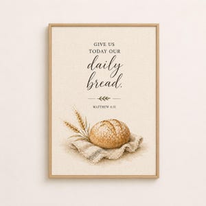 May include: Framed art print featuring a watercolor illustration of a loaf of bread on a linen napkin, with wheat stalks. The text reads "GIVE US TODAY OUR daily bread." and "MATTHEW 6:11". The frame is a light brown color.