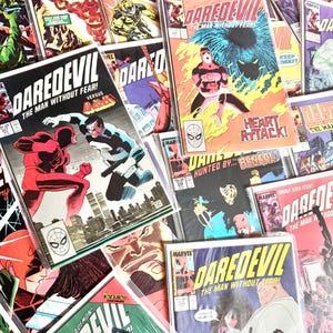 Puede incluir: Una colección de cómics vintage de Marvel con el superhéroe Daredevil. Las portadas muestran ilustraciones vibrantes de escenas llenas de acción, con texto en negrita y el icónico logotipo de Daredevil. Los cómics están en fundas protectoras.