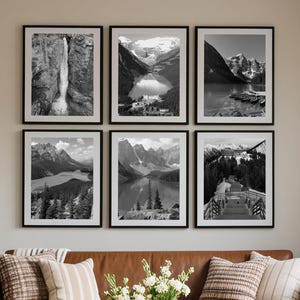 Peut inclure: Un salon avec un canapé en cuir marron, des coussins et une couverture. Six tirages de paysages en noir et blanc encadrés sont accrochés au-dessus. Une table basse ronde en bois avec des vases blancs et des fleurs.