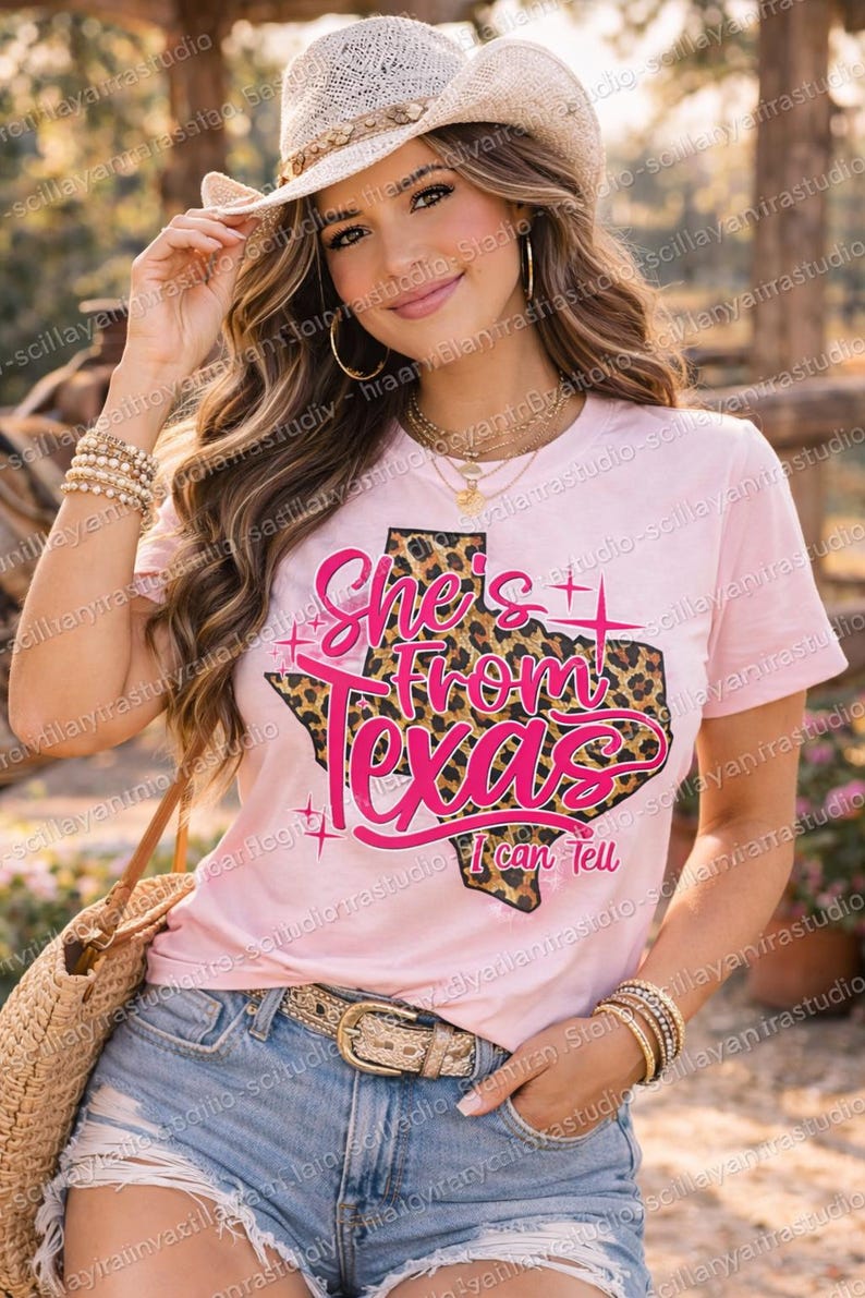 May include: A pink t-shirt with the text "She's From Texas I can Tell" in a pink font, with a leopard print Texas outline. The model is wearing a straw hat and denim shorts.
