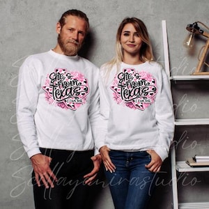 K&ouml;nnte beinhalten: Zwei Personen tragen wei&szlig;e Sweatshirts mit einem rosa-schwarzen Aufdruck mit der Aufschrift "She's From Texas I Can Tell". Die Grafik hat die Form des Bundesstaates Texas. Die Person links tr&auml;gt eine schwarze Hose, die Person rechts blaue Jeans.