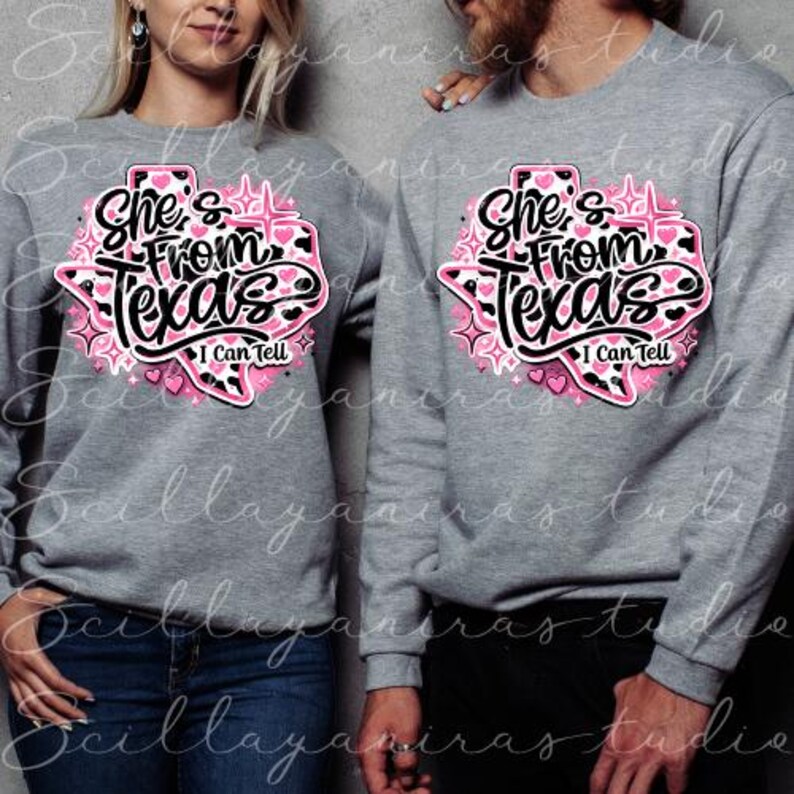 K&ouml;nnte beinhalten: Zwei graue Sweatshirts mit dem Text "She's From Texas I Can Tell" in einem rosa-schwarzen Design in Form des Bundesstaates Texas. Das Design enth&auml;lt Herzen und Sterne. Die Sweatshirts werden von zwei Personen getragen.