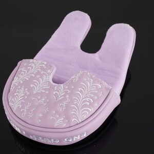 May include: A lavender golf putter head cover with a U-shaped top and a decorative floral pattern in white. The cover has the words "END OVER" printed on the bottom edge. The background is black.