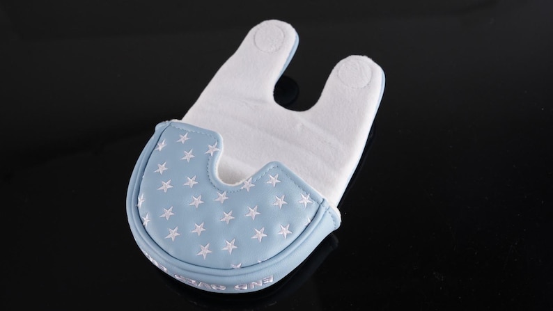 May include: A baby bib with a light blue front featuring white embroidered stars. The bib has a white, absorbent interior and a curved shape to fit around the neck. The bib is designed to catch spills and dribbles.
