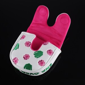 Puede incluir: Una funda para putter tipo mallet de color blanco con un patr&oacute;n de flores rosas y cactus verdes. El interior est&aacute; forrado con tela de color rosa brillante. El lateral de la funda muestra el texto bordado en verde END OVER END.