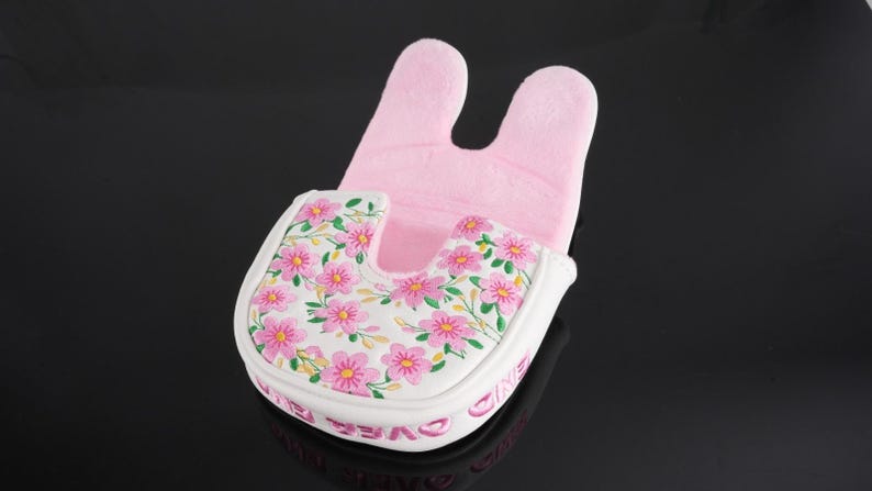 May include: A mallet-style putter headcover featuring a white base with a pink floral pattern and green stems. The interior is lined with soft light pink fabric. The side of the headcover displays the text "GAME OVER" in pink lettering.