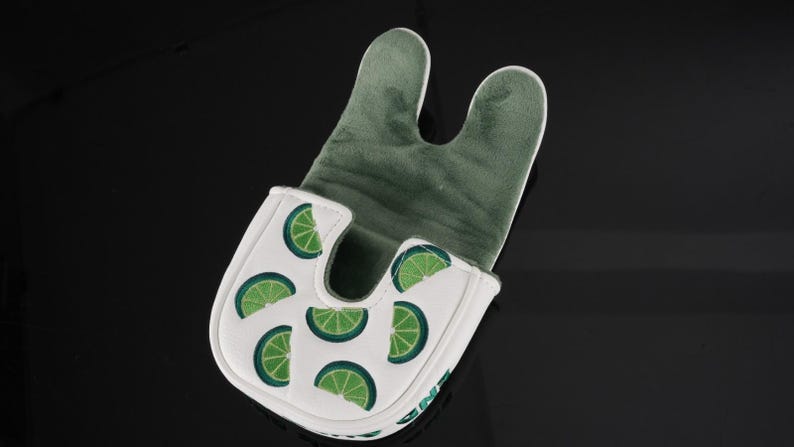 Pu&ograve; includere: Un copri-putter bianco con un motivo ripetuto di fette di lime verdi. L'esterno &egrave; bianco con una finitura liscia, mentre l'interno &egrave; foderato con un morbido tessuto felpato verde scuro. Il copri-putter presenta un caratteristico design a U.