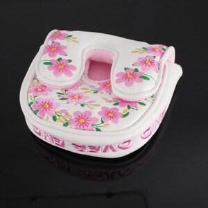 May include: A white mallet putter headcover featuring a pink floral pattern with green stems and leaves. The cover has a U-shaped opening and pink interior lining. The side of the white cover features the text "GAME OVER" embroidered in pink.
