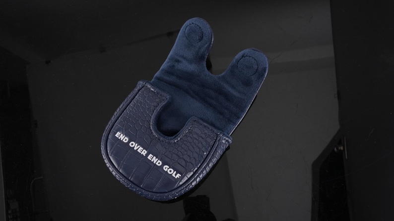 May include: A dark navy blue golf putter headcover featuring a textured crocodile skin pattern on the exterior and a soft fabric interior. The text END OVER END GOLF is printed in white on the front of the cover, which has a U-shaped opening.