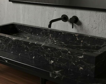 May include: A rectangular black marble sink with white veining, mounted on a matching countertop. The sink has a minimalist design, with a matte black faucet and fixtures. The bathroom fixture is set against a neutral gray wall.