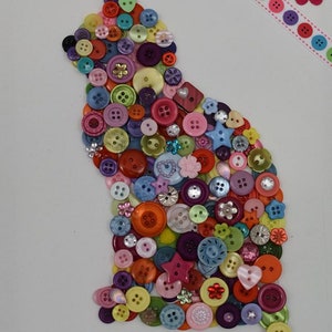 May include: A colorful cat silhouette made from buttons of various colors, shapes, and sizes. The cat is outlined with buttons and has a tail.