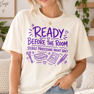 Peut inclure: Un t-shirt couleur crème avec un texte violet indiquant READY BEFORE THE ROOM STERILE PROCESSING NIGHT SHIFT. Le motif comprend des illustrations graphiques d'instruments médicaux, notamment des ciseaux, un plateau et des pinces.