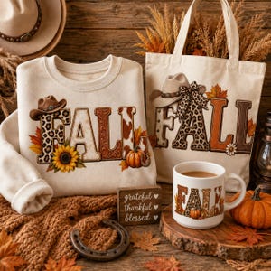 Peut inclure: Un sweat-shirt crème et un sac fourre-tout en toile assorti, tous deux ornés du mot FALL dans un imprimé western avec des motifs léopard, peau de vache et floraux. Une tasse en céramique blanche affiche le même motif, avec un panneau en bois indiquant grateful thankful blessed et un fer à cheval en métal.