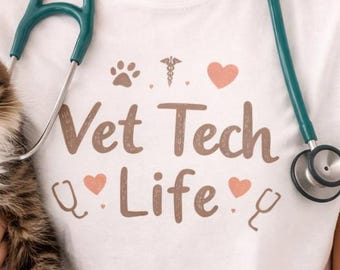 May include: A white t-shirt with the text "Vet Tech Life" in brown and pink, with a stethoscope around the neck. A person is holding a tabby cat. The person is smiling.