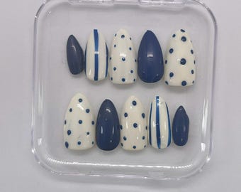 Unhas postiças simples em tons de azul marinho com bolinhas e listras.