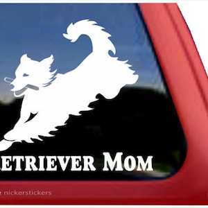 Op de afbeelding: Witte silhouet van een hond met een stok in zijn bek, die rent. De tekst "RETRIEVER MOM" staat onder de hond. De afbeelding is op een zwarte achtergrond.