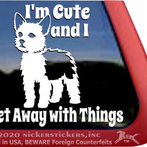 Può includere:  Adesivo in vinile bianco di un cane con il testo "I'm Cute and I Get Away with Things". L'adesivo è su un finestrino di un'auto rossa.