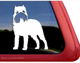 Op de afbeelding: Een witte vinyl sticker van een hond, waarschijnlijk een terriër, met een blauwgrijs gezicht en baard. De sticker zit op een raam met een rode lijst. De copyrightvermelding "© 2014 nickerstickers" is zichtbaar.