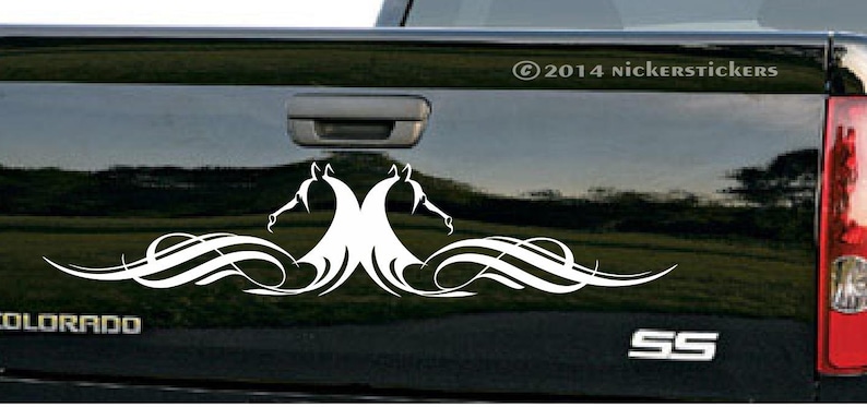 Puede incluir: Calcoman&iacute;a de vinilo blanco de dos cabezas de caballo estilizadas con l&iacute;neas fluidas, aplicada a la puerta trasera de una camioneta negra. La camioneta tiene los emblemas "COLORADO" y "SS".